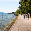 Urlauber schlendern die Promenade am Überlinger Minigolfplatz entlang. Im Wasser genießen Schwimmer eine Abkühlung. Noch herrscht Hitze.