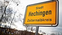Graue Wolken ziehen über das Ortseingangsschild von Hechingen hinweg.