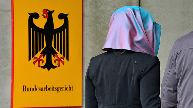 Eine junge Frau mit Kopftuch geht am Behördenschild mit der Aufschrift «Bundesarbeitsgericht» vorbei.