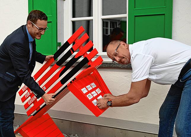 Bürgermeister Florian Zindeler (links) hält die Bank, während Gemeinderat Karlheinz Lehmann den Aufkleber der Gemeinde Hohenfels ...