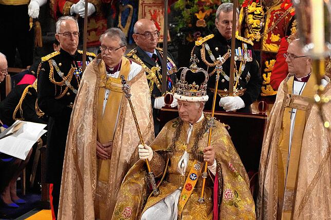 Über zwei Kilogramm wiegt der prunkvolle Kopfschmuck: König Charles III. sitzt mit der Edwardskrone und den beiden Zepter auf den Thron, ...