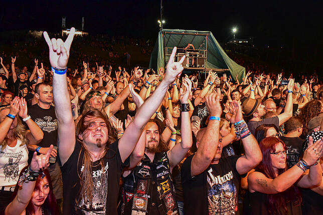 Die &bdquo;Pommesgabel&ldquo; zum Metalergruß in die Höhe gestreckt, feiern Fans von Heavy Metal Musik zwei Tage lang auf dem Metalacker.