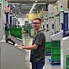 Sebastian König steht inmitten der riesigen Spritzgießmaschinen. Bedienen kann er sie als Verfahrensmechaniker.