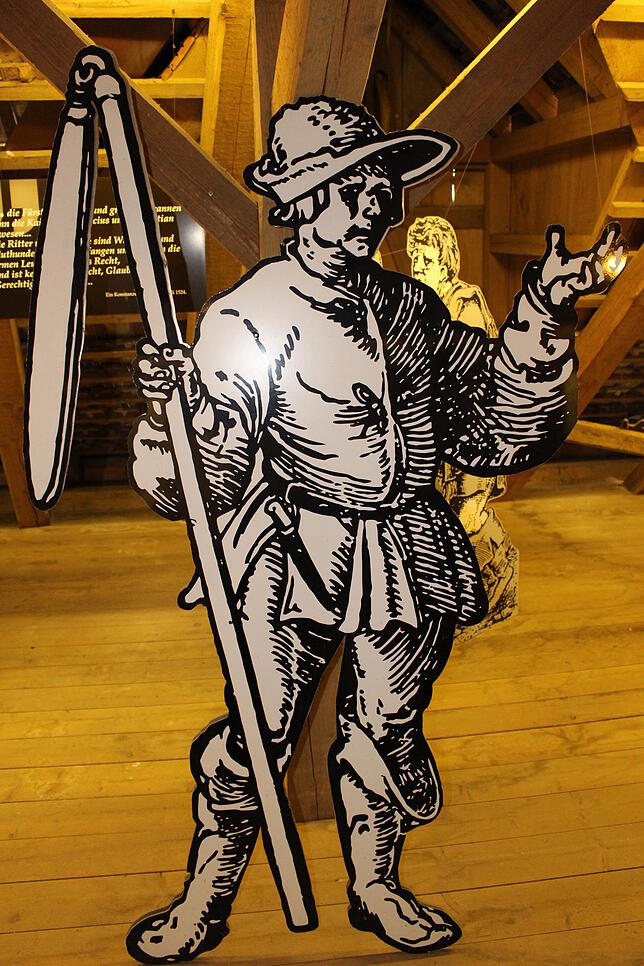 Historische Darstellung eines mit Dreschflegel bewaffneten Bauern im Hilzinger Ortsmuseum.