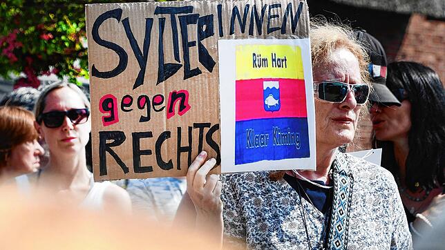 „SylterInnen gegen Rechts“ steht auf einem Schild, dass eine Frau in der Hand hält. Nach dem Rassismus-Eklat um ein Partyvideo haben ...