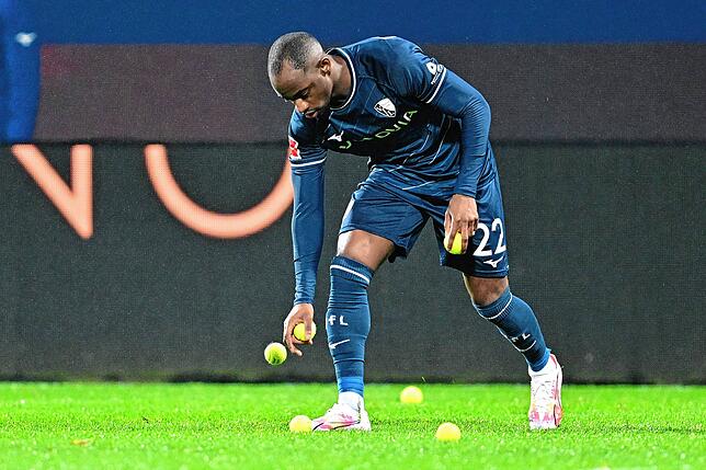 Bochums Christopher Antwi-Adjej sammelt während einer Unterbrechung beim Spiel gegen Bayern München Tennisbälle auf, die von Fans als ...