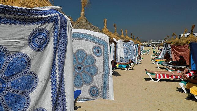 Menschen schützen sich auf Mallorca bei heißen Temperaturen mit Strandtüchern vor der Sonne am Strand von Arenal.