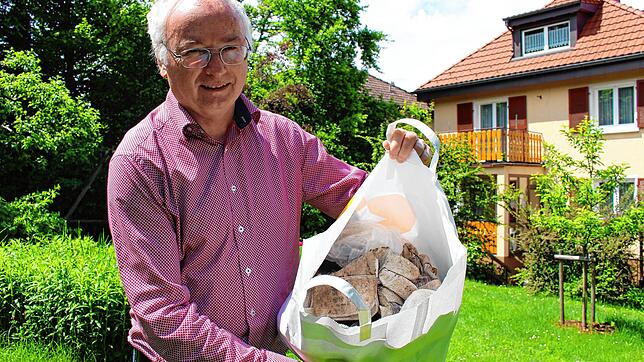 Elmar Mayer im Garten seines Hauses in der Talstraße. In der Tasche hat er lauter Unrat, der ihm von den Füchsen ans Haus geschleppt wurde.
