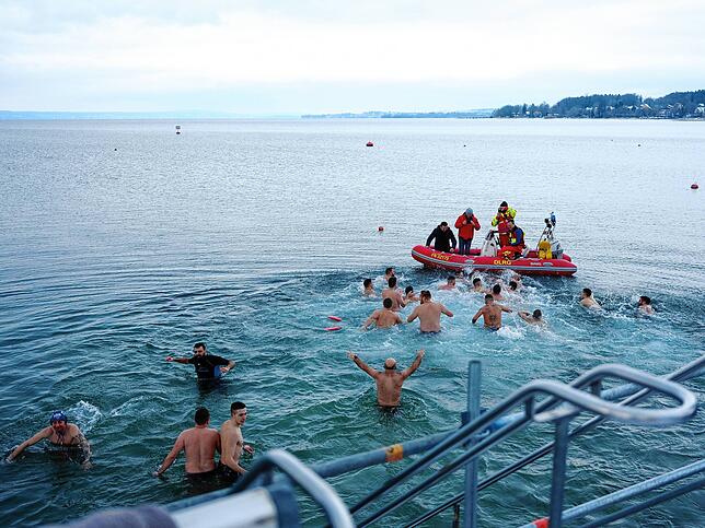 Die Männer springen ins Wasser und schwimmen zum Kreuz auf dem Boot.