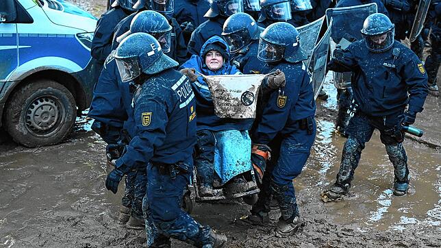 Polizisten tragen einen Aktivisten bei der Demonstration von Klimaaktivisten am Rande des Braunkohletagebaus bei Lützerath weg. Die ...