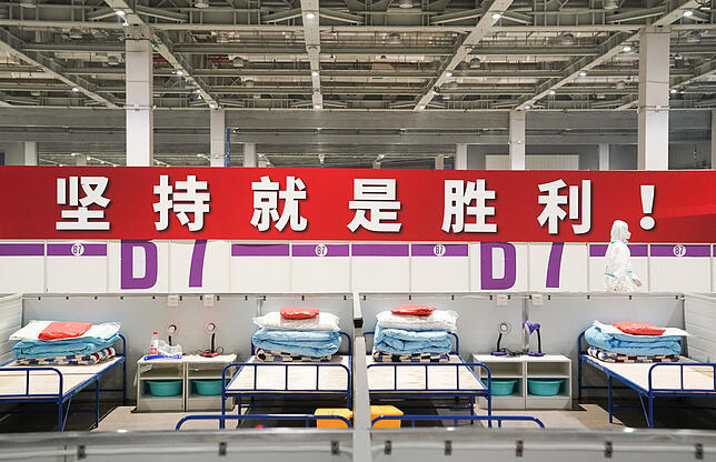 Shanghai: Ein Arbeiter in Schutzkleidung geht an einem Banner mit der Aufschrift &bdquo;Hartnäckigkeit ist der Sieg&ldquo; vorbei, das ...