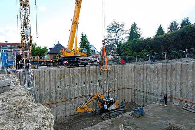 Damit der Bagger beim Hochheben von den Ketten nicht zerquetscht wird, fügen die Bauarbeiter eine sogenannte Traverse zwischen die ...