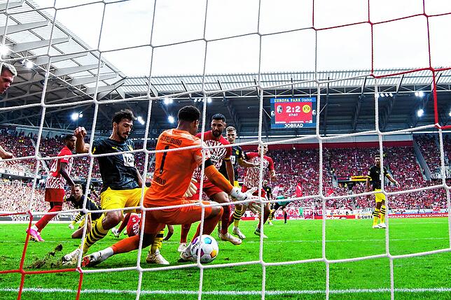 Dortmunds Mats Hummels (l) macht das Tor zum 2:3 gegen Freiburgs Torwart Noah Atubolu.