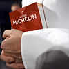 Ein Koch hält den Restaurantführer Guide Michelin in der Hand.