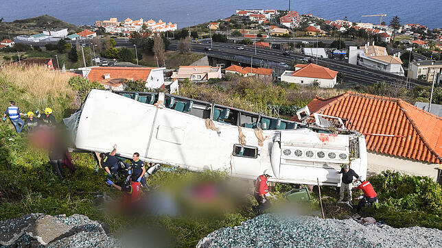 Rettungskräfte stehen nach einem schweren Busunglück auf der portugiesischen Ferieninsel Madeira an dem Bus. Bei dem Busunglück auf der ...