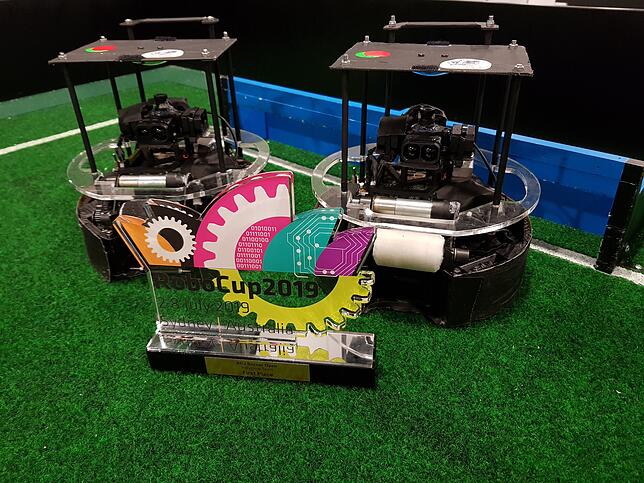 Das siegreiche Roboter-Duo des Entwicklerteams Sprenger/Preus mit gewonnenem Weltermeisterschaftspokal.