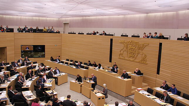 Der Blick von der Zuschauerbühne in den Plenarsaal. An der Wand das Staatswappen von Baden-Württemberg, darunter das Präsidium.