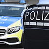 Ein Polizist steht vor dem Dienstwagen (Symbolbild). Nach zwei nächtlichen Angriffen mit einem Pfefferspray und einem Gartenwerkzeug auf ...