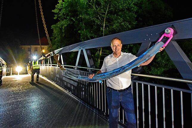 Hüfingens Bürgermeister Michael Kollmeier hilft beim Lösen der Tragseile von der fertig platzierten Brücke.