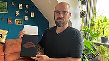 Jonas Fehlinger zeigt einen Abdruck seines Plakats in Kleinformat.
