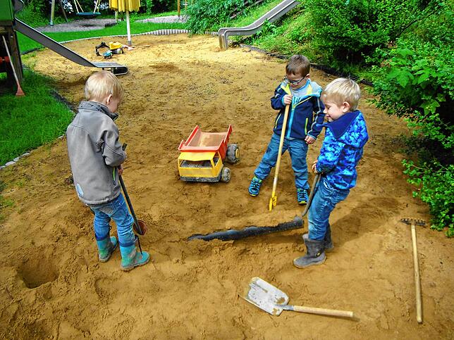 Drei Jungen beim Spielen im Sand mit Bagger und Schaufel im Kindergarten Hepbach.
