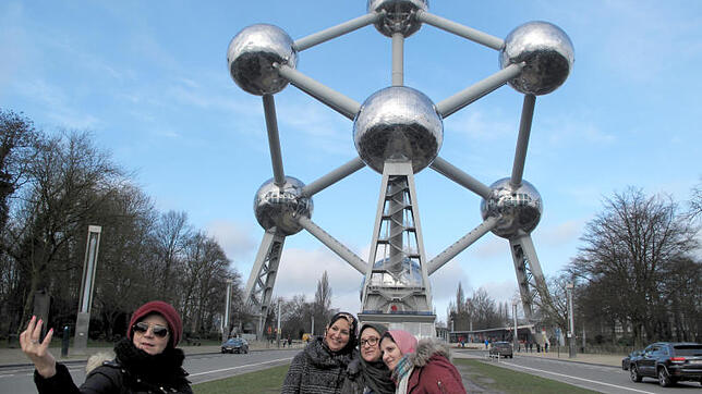 Touristinnen fotografieren sich vor dem Atomium in Brüssel, das dort seit 60 Jahren steht und Besucher fasziniert.