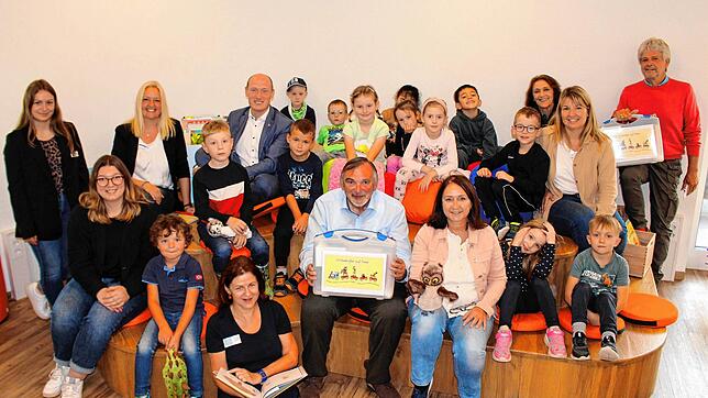 Kinder und Erzieherinnen der Kita Stadtkäfer nehmen einen Vorlesekoffer von Vertretern des Landratsamts, Bürgerstiftung und Bibliothek ...