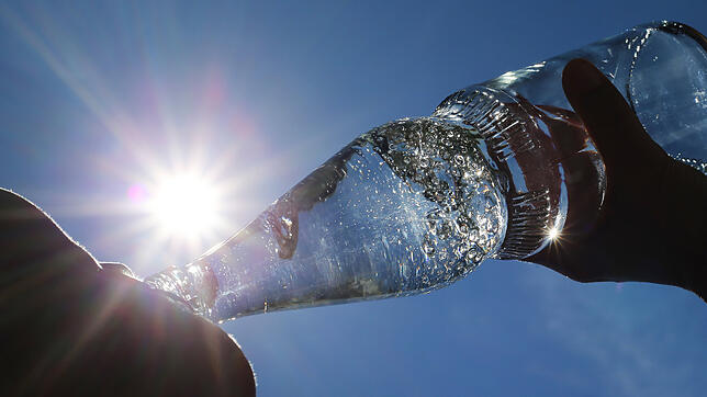 Eine Frau nimmt gegen die Hitze einen kräftigen Schluck aus einer Flasche Mineralwasser.