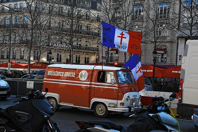 Zwei französische Nationalfahren, auf denen ein Gaullistenkreuz gedruckt ist, werden aus dem Fahrzeug eines Protestteilnehmers gehalten. ...