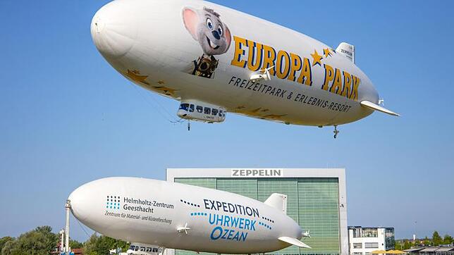 Flugbetrieb vor der Zeppelin-Halle in Friedrichshafen: Der Zeppelin "Bodensee" gewinnt an Höhe, während das Luftschiff ...