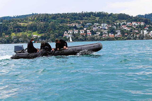 Der Bootsführer lenkt das Boot möglichst dicht an den Soldaten im Wasser heran. Die anderen helfen ihm auf das Boot.