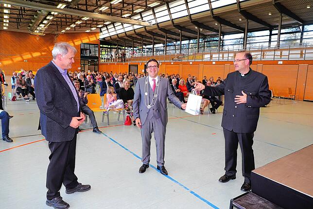 Der evangelische Pfarrer Thomas Weber (links) und der katholische Pfarrer Matthias Schneider (rechts) überreichten Dominik Männle eine Uhr.