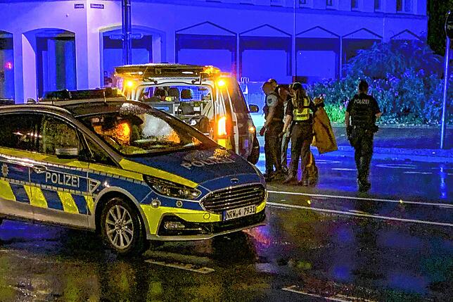 Am späten Abend stellt sich ein Mann (hinten verdeckt zwischen Polizisten) bei der Polizei auf offener Straße und gibt an der Täter zu sein.