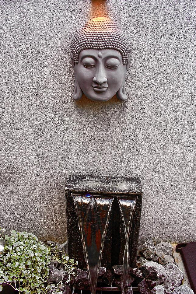 Ein Buddhakopf schwebt über dem Wasserfallbrunnen.