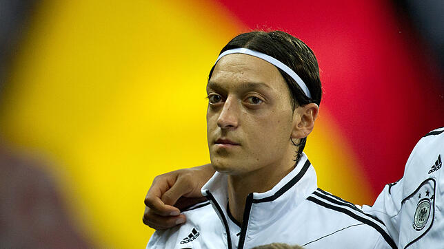 Mesut Özil steht vor einer Deutschlandfahne.