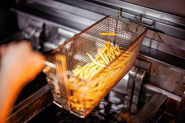 Eine Mitarbeiterin nimmt in einer Filiale der Fastfoodkette McDonald&lsquo;s einen Korb mit Pommes Frites aus der Friteuse. (Archivbild)