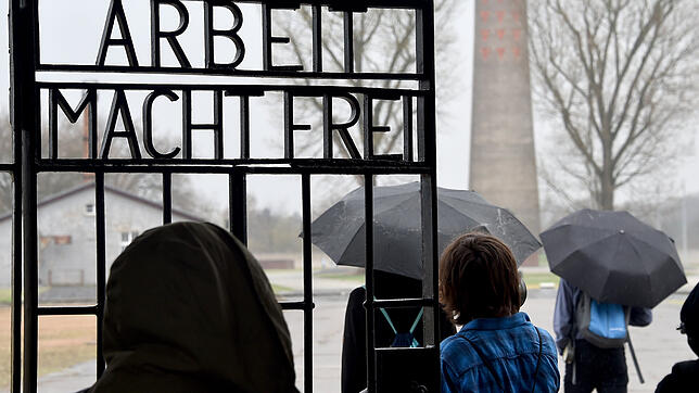 Besucher gehen durch das Tor des früheren Konzentrationslagers Sachsenhausen mit der Aufschrift "Arbeit macht frei". Bild: dpa