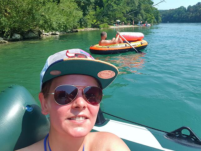 Reporterin Sira Huwiler schützt sich auf dem Schlauchboot mit Sonnenbrille und Mütze vor der Sonne. Bild: Sira Huwiler
