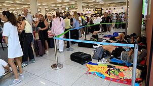 Reisende stehen im Flughafen von Palma de Mallorca Schlange. Ein heftiges Unwetter brachte den Flugverkehr durcheinander.
