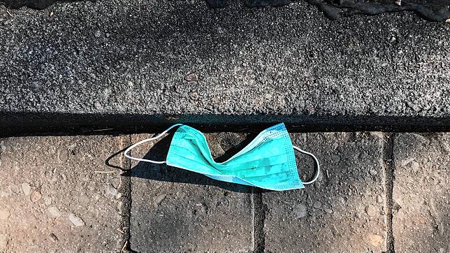 Eine Mund-Nasen-Maske liegt auf der Straße. Ein Zahnarzt im Landkreis Waldshut hat in seiner Praxis Hinweisschilder aufgehängt, dass ...