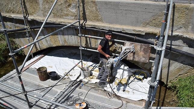 Karl-Otto Stauß bohrt Löcher für Metallstäbe in die Brücke beim Stockacher Freibad, um diese zu stabilisieren.