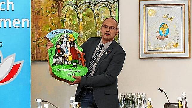 Nikolaus Arnold zeigt das Gastgeschenk, eine von Samuel Kammerer und Werner Oppelt gestaltete Holztafel. Bilder: Hans-Jürgen Kommert