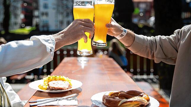 Zwei Männer stoßen in einem Tübinger Biergarten an.