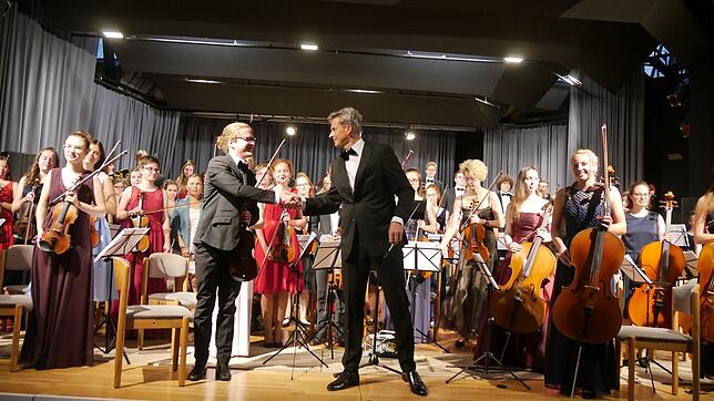 Bevor das Konzert der Jungen Philharmonie Oberschwaben begann, reichte Dirigent Alban Beikircher (rechts) dem ersten Violinisten ...