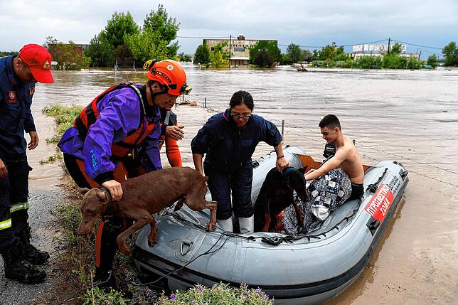 Feuerwehrleute mit einem Schlauchboot evakuieren Menschen und ihre Hunde aus überfluteten Gebäuden in Larissa.