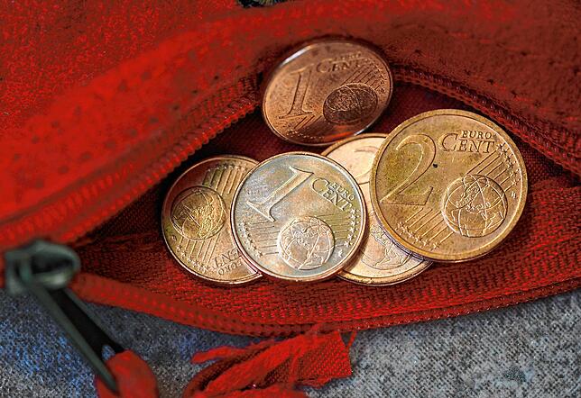 Ein- und Zwei-Cent-Münzen liegen in einer roten Geldbörse. Kinder sollten früh lernen, zu sparen &ndash; auch mit kleinen Beträgen.