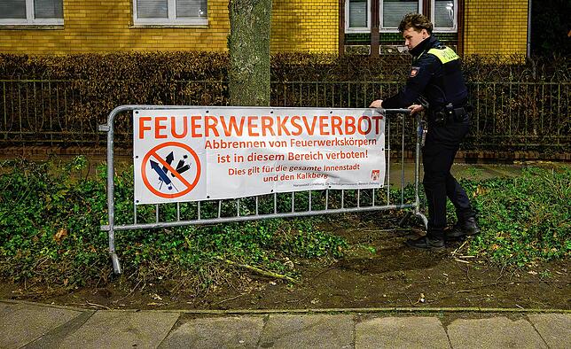Ein Polizist richtet in Lüneburg in der Silvesternacht einen Banner mit dem Aufschrift “Feuerwerksverbot„ wieder auf.