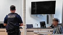 Der 33-Jährige auf der Anklagebank. Ein Justizbeamter hat sich im Gerichtssaal vor ihm positioniert.