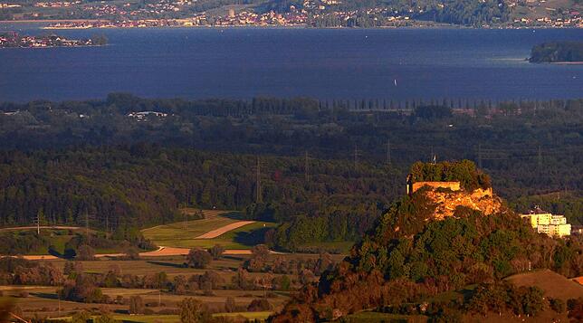 Blick vom Hohenhewen aus: Der Sonnenuntergang taucht den Hohenkrähen in goldenes Licht. Am oberen Bildrand ist der Zeller See zu erkennen.