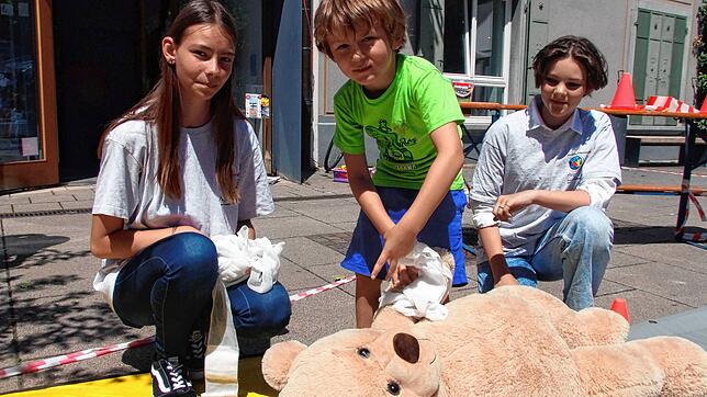 Levi (Mitte) kümmert sich um einen Teddy und wird dabei von Monika Reiband (links) und Berta Maucher vom Jugendrotkreuz unterstützt.